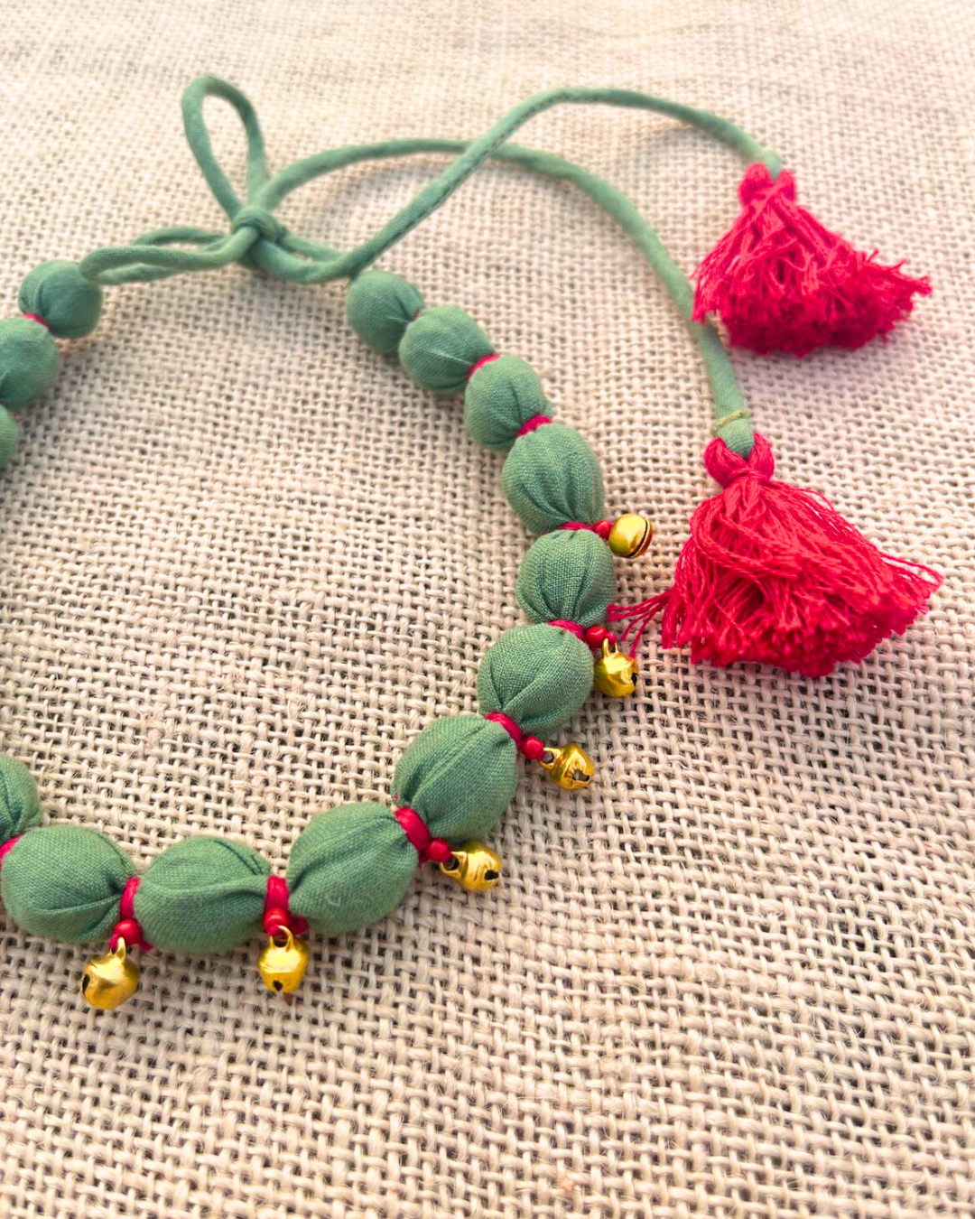 Green beaded necklace with red tassels
