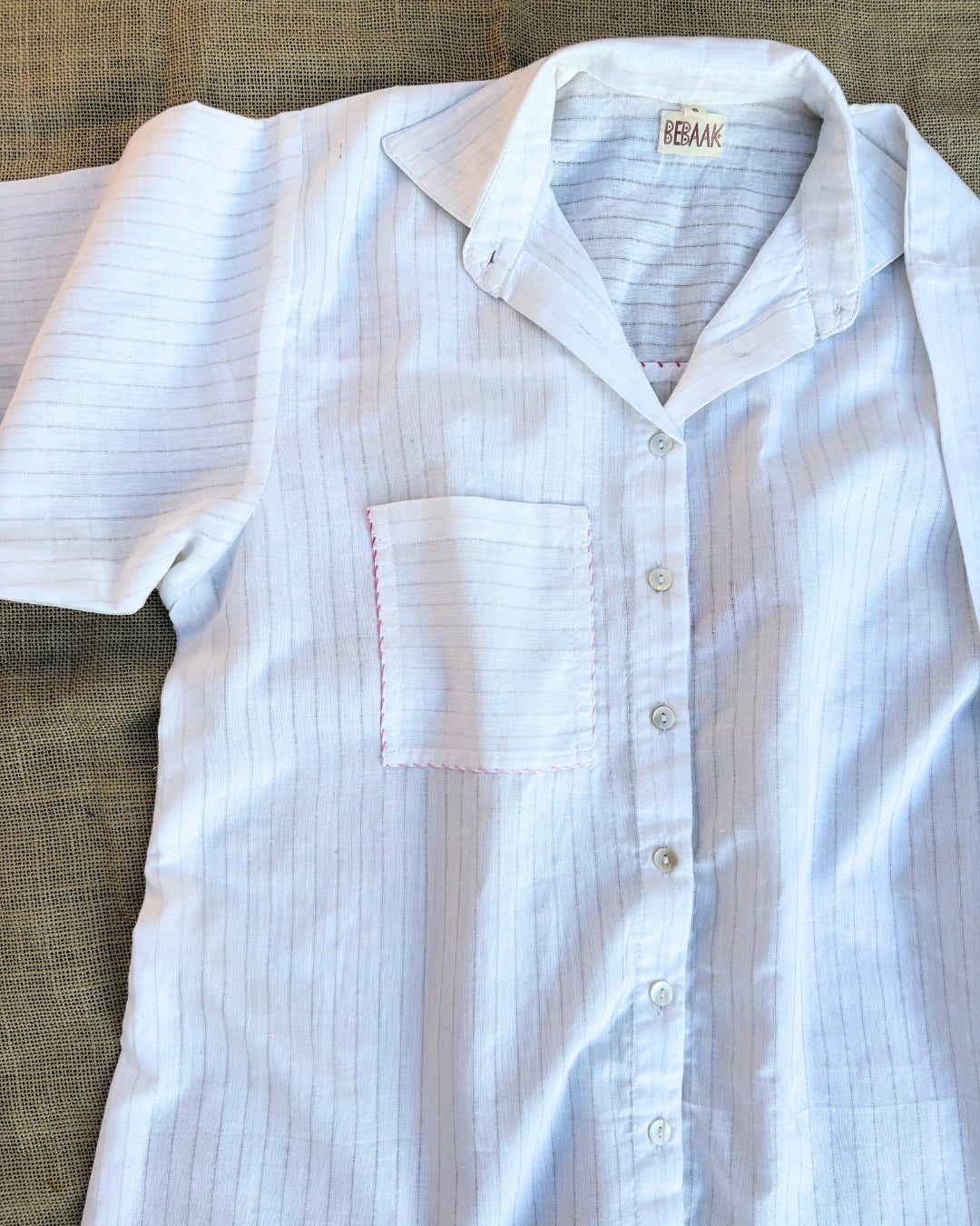 White short-sleeve shirt with blue stripes on a textured surface