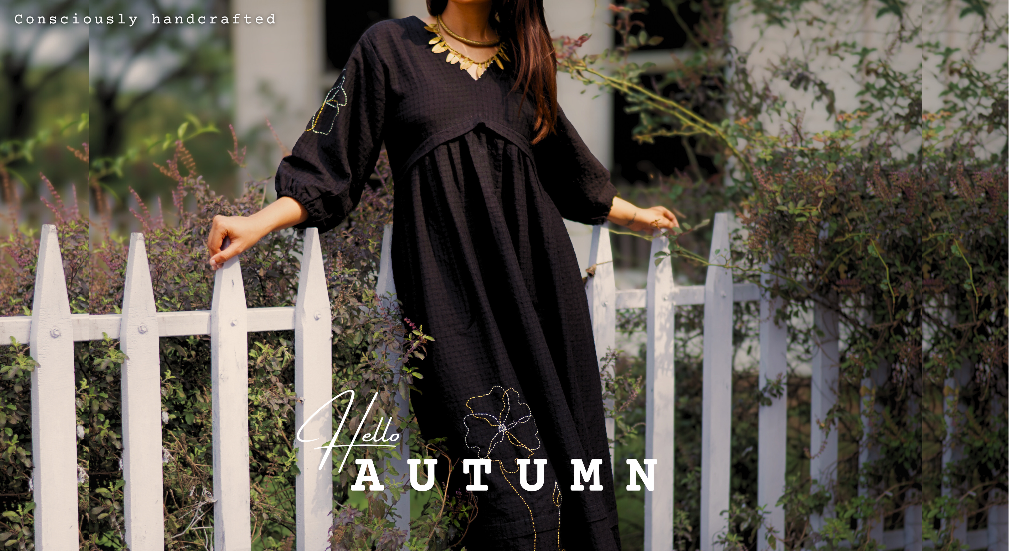 Woman in a black dress standing by a white picket fence 