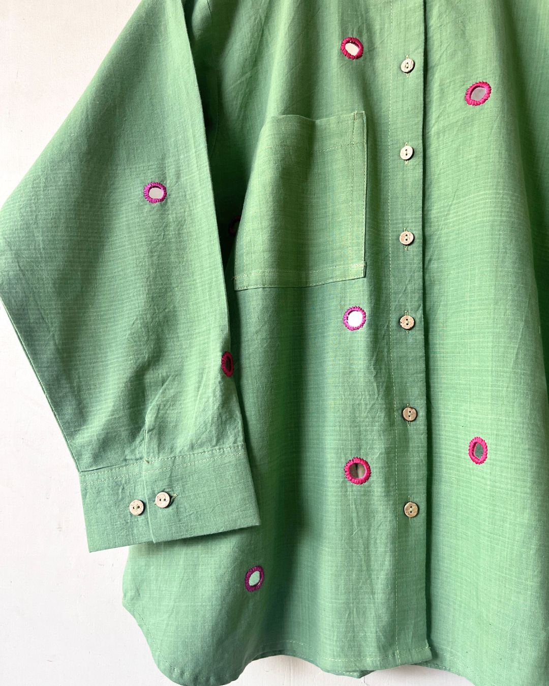 Green shirt with decorative buttons on a white background
