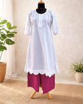 White kurta with  scalloped hem and pink pants on a mannequin against a neutral background.