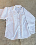 White button-up shirt with subtle pattern on a textured surface