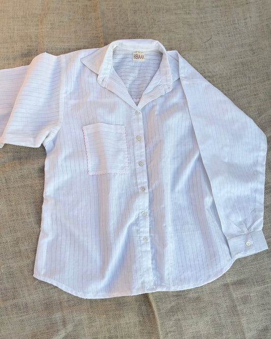 White button-up shirt with subtle pattern on a textured surface